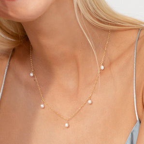 Gold pearl drops necklace shown worn around a neck