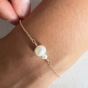 Gold mother and child pearl bracelet shown worn around a wrist