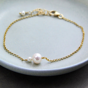 Gold mother and child pearl bracelet shown on a dish