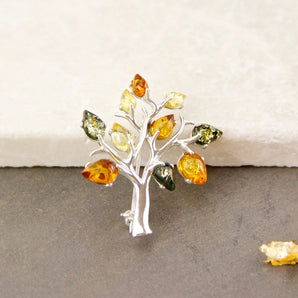 Sterling Silver Amber Tree Of Life Brooch displayed against contrasting white and grey surfaces