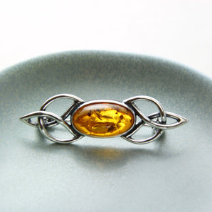 Baltic Amber Celtic Brooch displayed on a dish