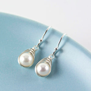 All Wrapped Up White Pearl and Silver Earrings shown hooked over the edge of a dish