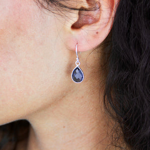 Sapphire earrings with silver hooks shown worn on a model's ear