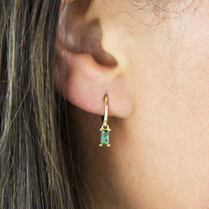 Gold plated Baguette Birthstone Petite Hoop Earrings with May birthstone shown worn in a model's ear