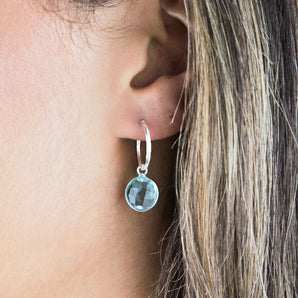 Aquamarine semi-precious birthstone earring with silver hoop shown worn on the model's ear