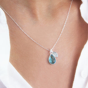 Pear shaped birthstone and leaf charm on sterling silver chain worn by a model
