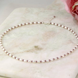 Sterling Silver Seed Pearl And Birthstone Necklace displayed on a marbled surface