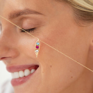 Gold peapod necklace shown across a model's face
