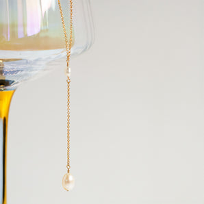 Gold Filled Pearl Lariat Necklace shown suspended from decorative glass