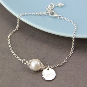 Wrapped Pearl Silver Bracelet with engraved disc charm displayed against a dish