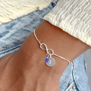 Sterling Silver Infinity Birthstone Sliding Bracelet with September birthstone and engraved disc charm shown worn around a model's wrist
