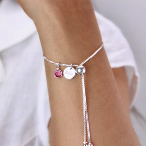 Silver adjustable bracelet with birthstone and engraved disc charm around a wrist
