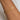 Gold snake bracelet on a person'swrist against a neutral background