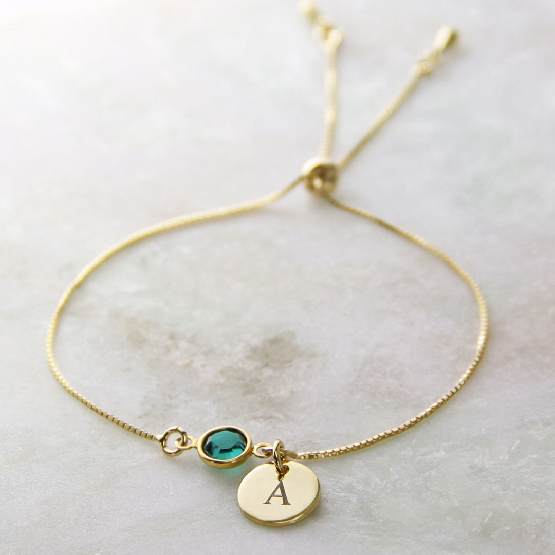Gold bracelet with emerald birthstone and engraved disc charm