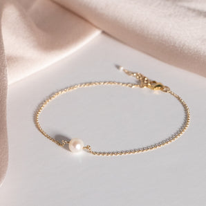Gold Filled Pearl Bracelet displayed on a white surface with a pale pink fabric background