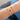 Gold bracelets with baguette birthstones on a wrist against a blue fabric background