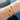 Gold bracelet with birthstones on a wrist against a blue fabric background
