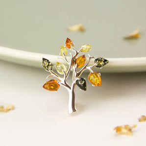 Sterling Silver Amber Tree Of Life Brooch displayed against the side of a dish