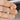Silver heart-shaped earrings held between fingers against a blurred background