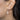 Close-up of an ear wearing a silver star earring with a pearl accent.