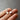 Silver drop star earrings held between fingers against a grey background