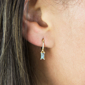 Gold plated Baguette Birthstone Petite Hoop Earrings with March birthstone shown worn in a model's ear