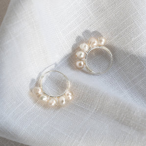 Sterling Silver Pearl Small Hoop Earrings displayed on a white fabric background