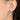 Close-up of an ear wearing a round earring with a purple border and green gemstone.