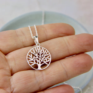 Round Tree of Life pendant on a silver chain shown against fingertips for size