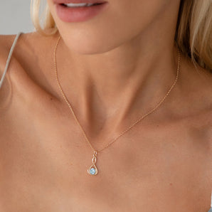 Gold necklace with birthstone in an infinity setting shown on a model