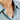 Silver necklace with a round angel wings pendant worn by a person in a light blue shirt.