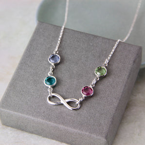 Silver necklace with infinity charm and birthstones on a gift box